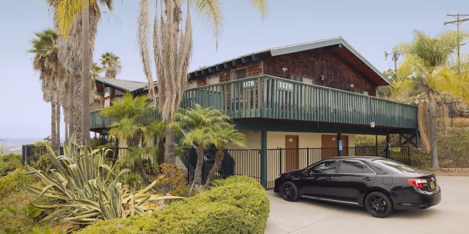 Exterior view of Mountain View Manor Assisted Living, a two-story building with balcony and parked car.