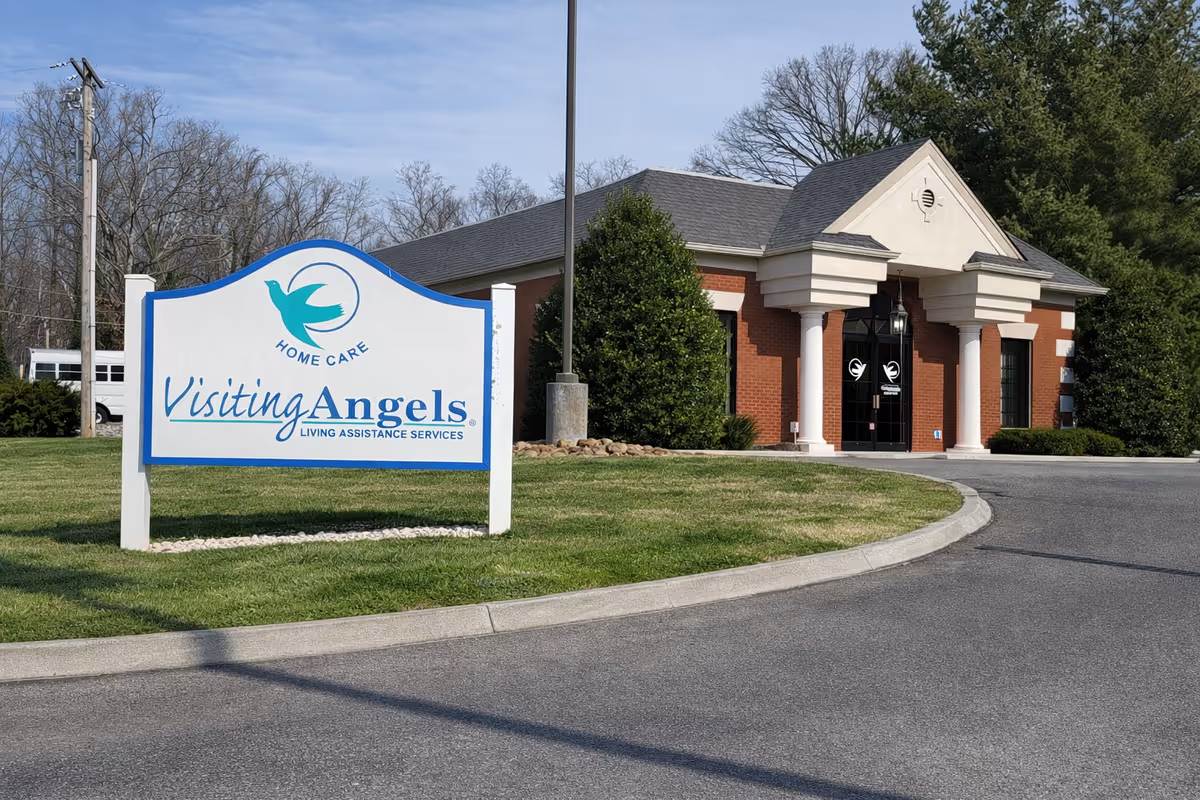 Exterior view of Visiting Angels building with front entrance, brick columns, and a large sign.