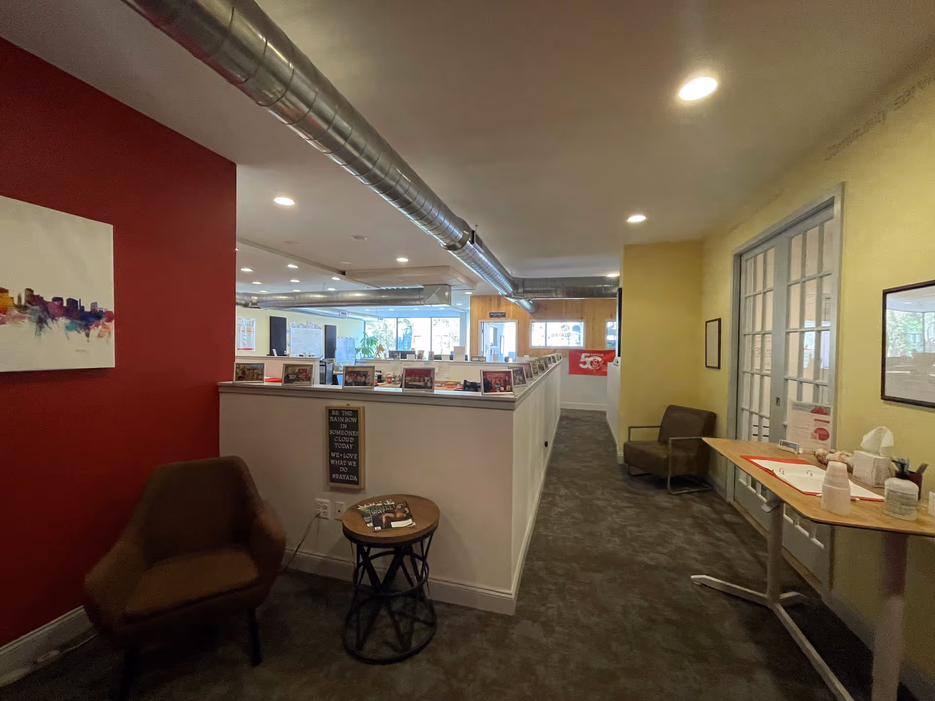 Interior facility lounge with cubicles, chairs, and a table in BAYADA Assistive Care.