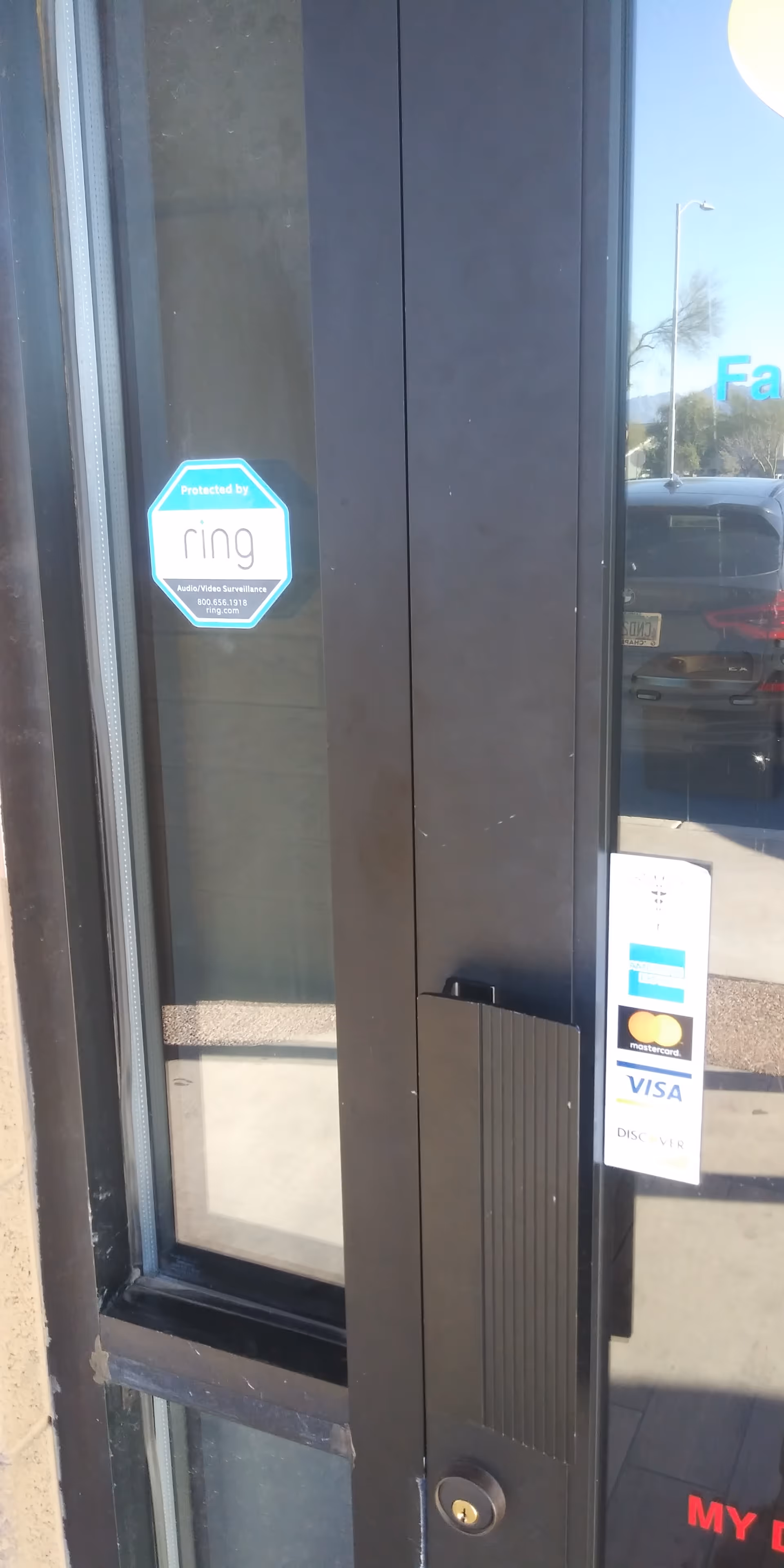 View of a building entrance door with glass panels and reflections.