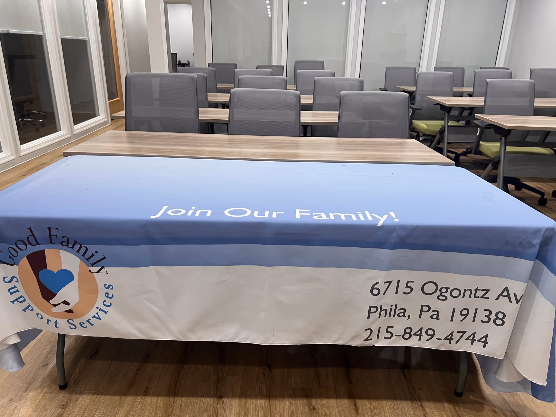 Interior conference room with rows of desks and a blue banner reading Join Our Family.
