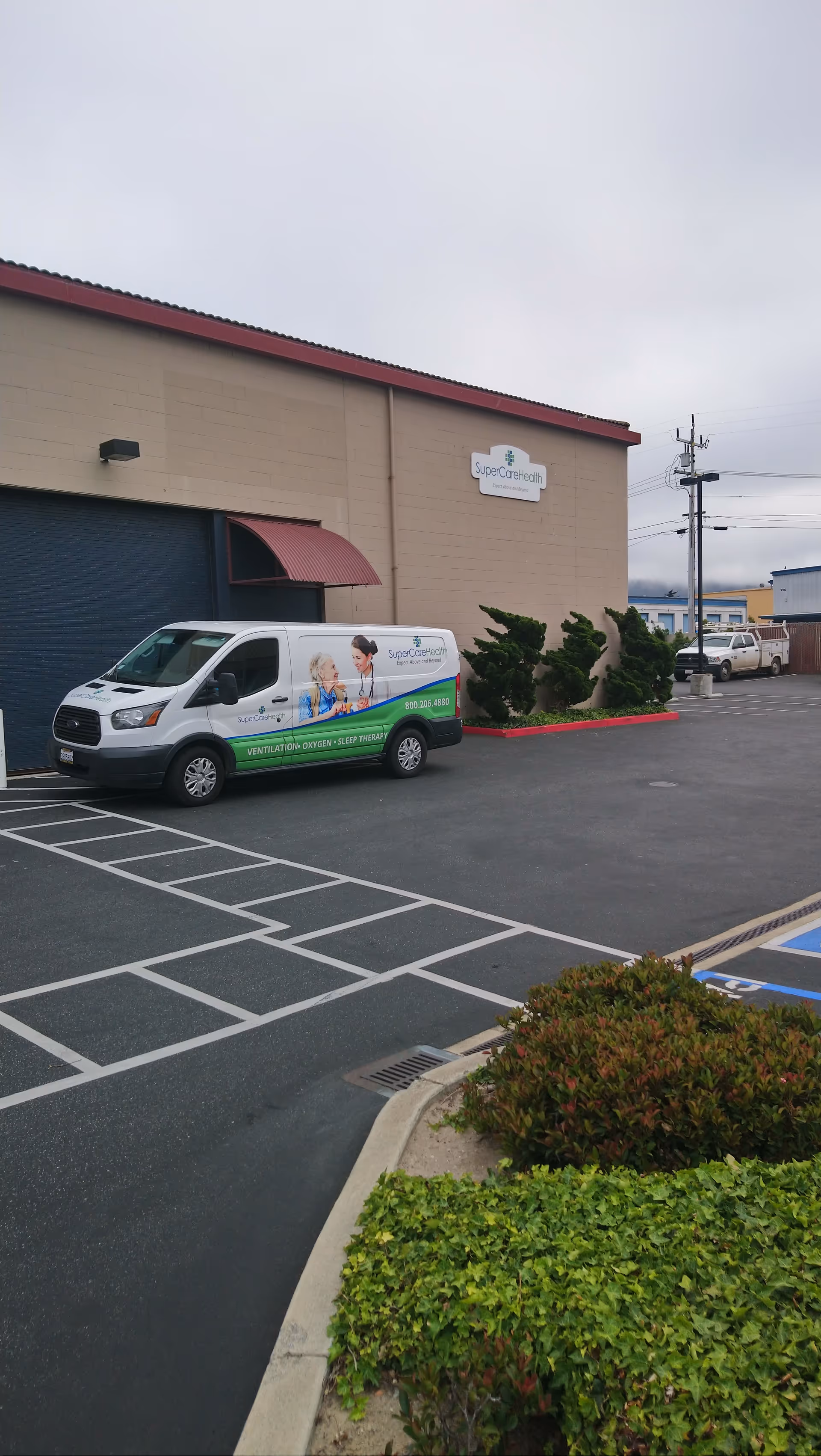 Exterior view of SuperCare Health building with a branded van parked outside.