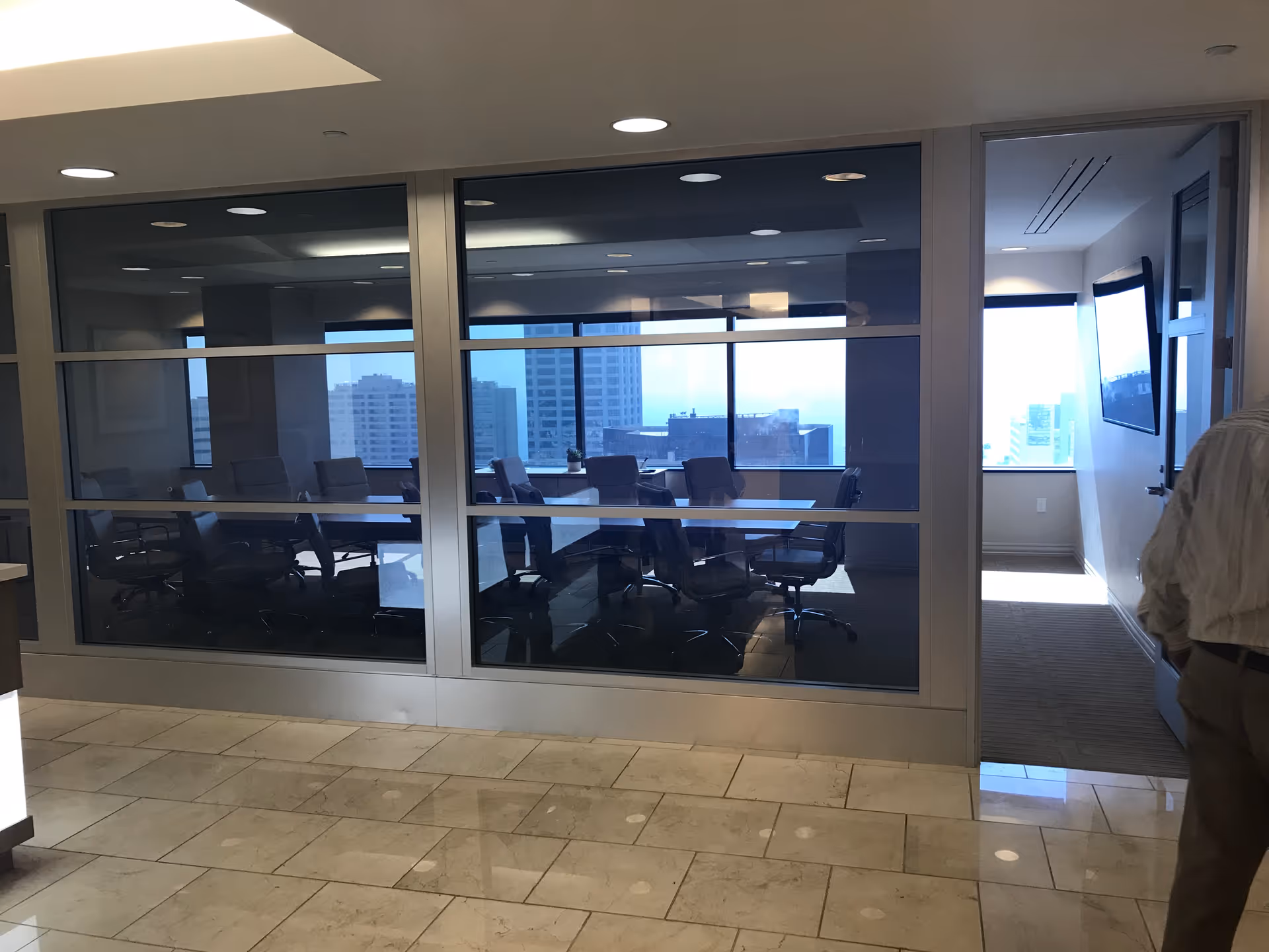 Glass-walled conference room inside a high-rise building with a long table and chairs