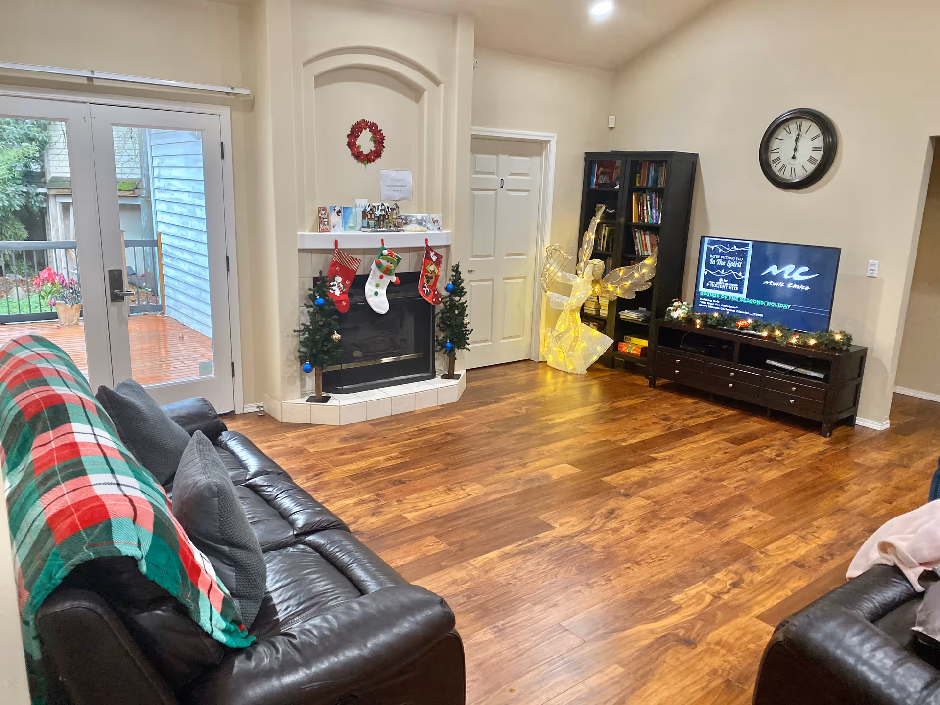 Cozy living room with leather couches, fireplace, Christmas stockings, and a TV.