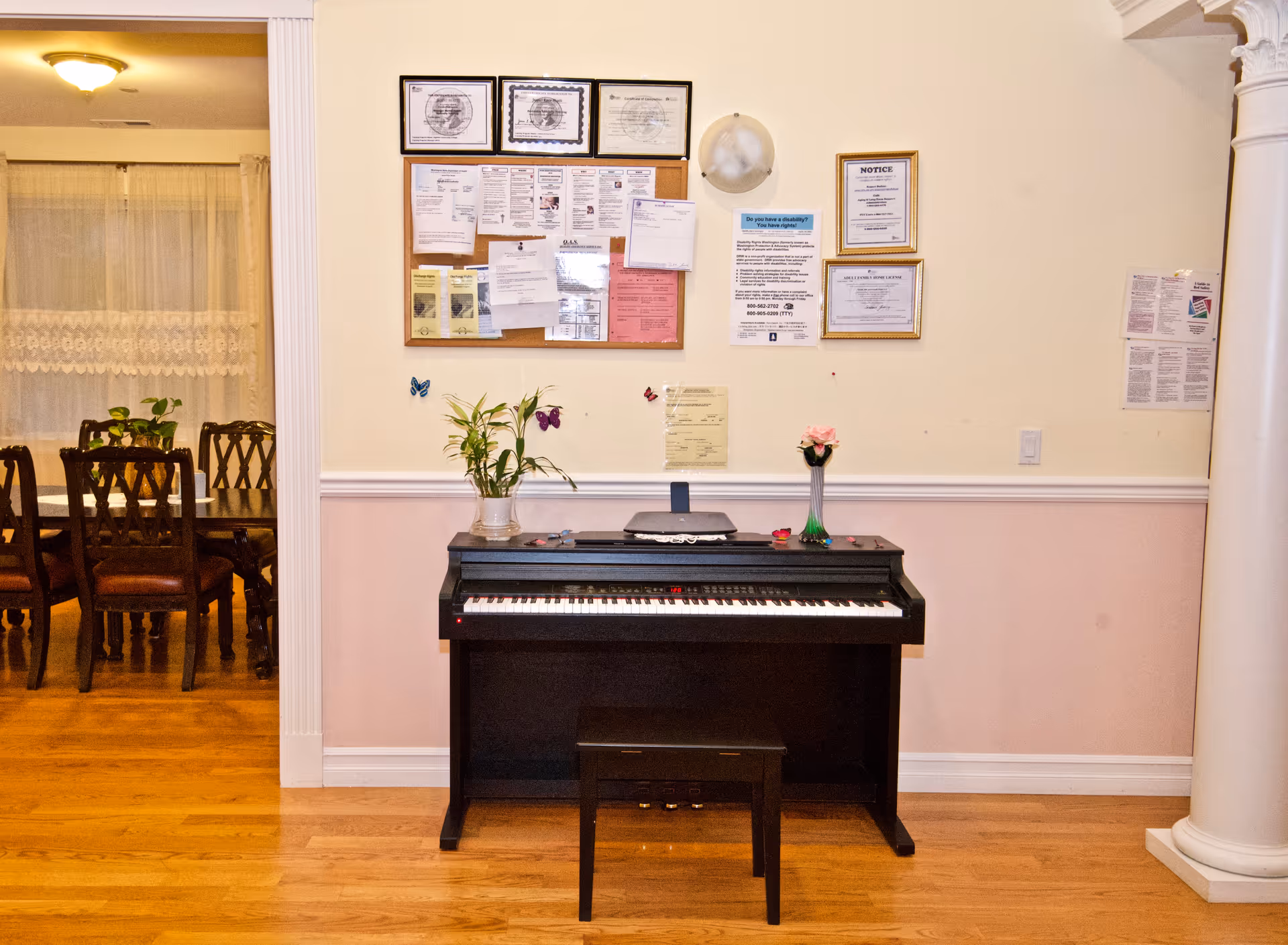Piano with stool sits under bulletin board in a senior living facility hallway.