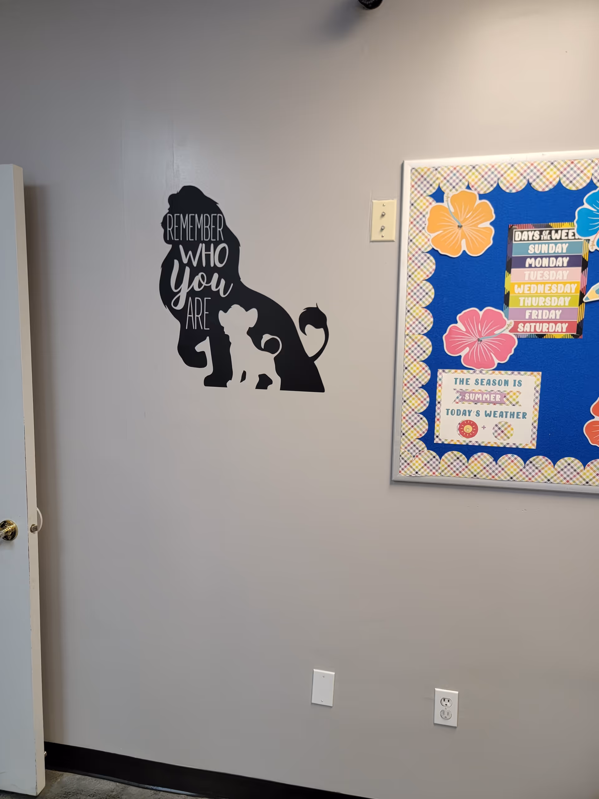 Interior wall with elephant silhouette mural and colorful bulletin board in a resident area.