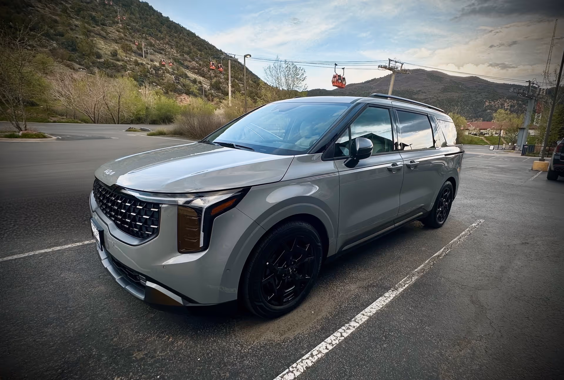Silver minivan parked diagonally in a large lot with mountains in the background.