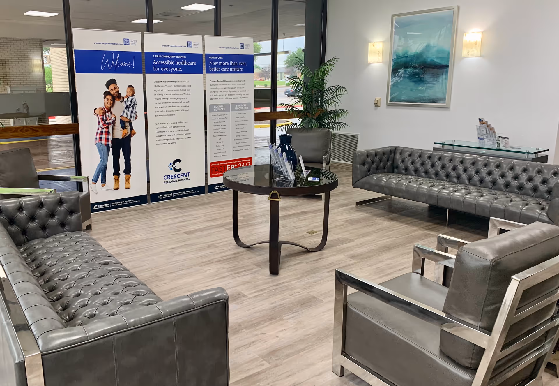 A Crescent Regional Hospital lobby with black leather seating, a glass table, and posters.
