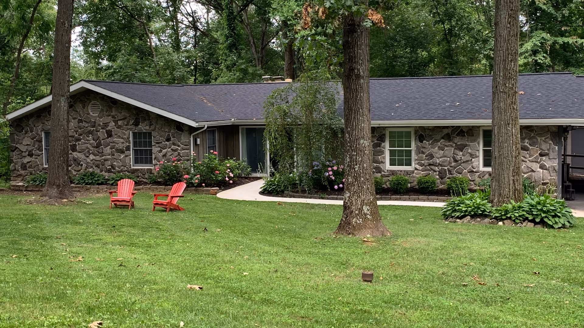 Stone facade building with a front lawn and two red Adirondack chairs.