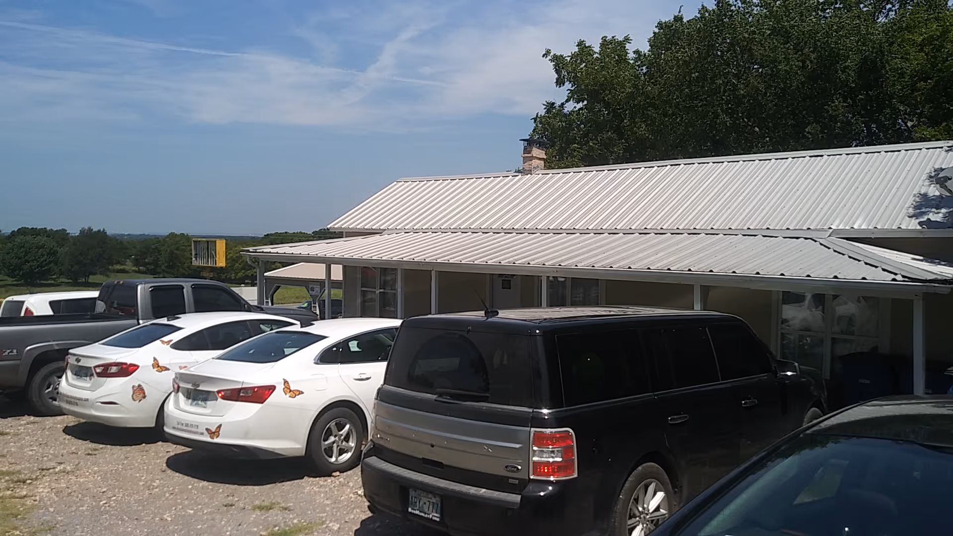Outside view of a single-story hospice facility with a parking lot and several cars.