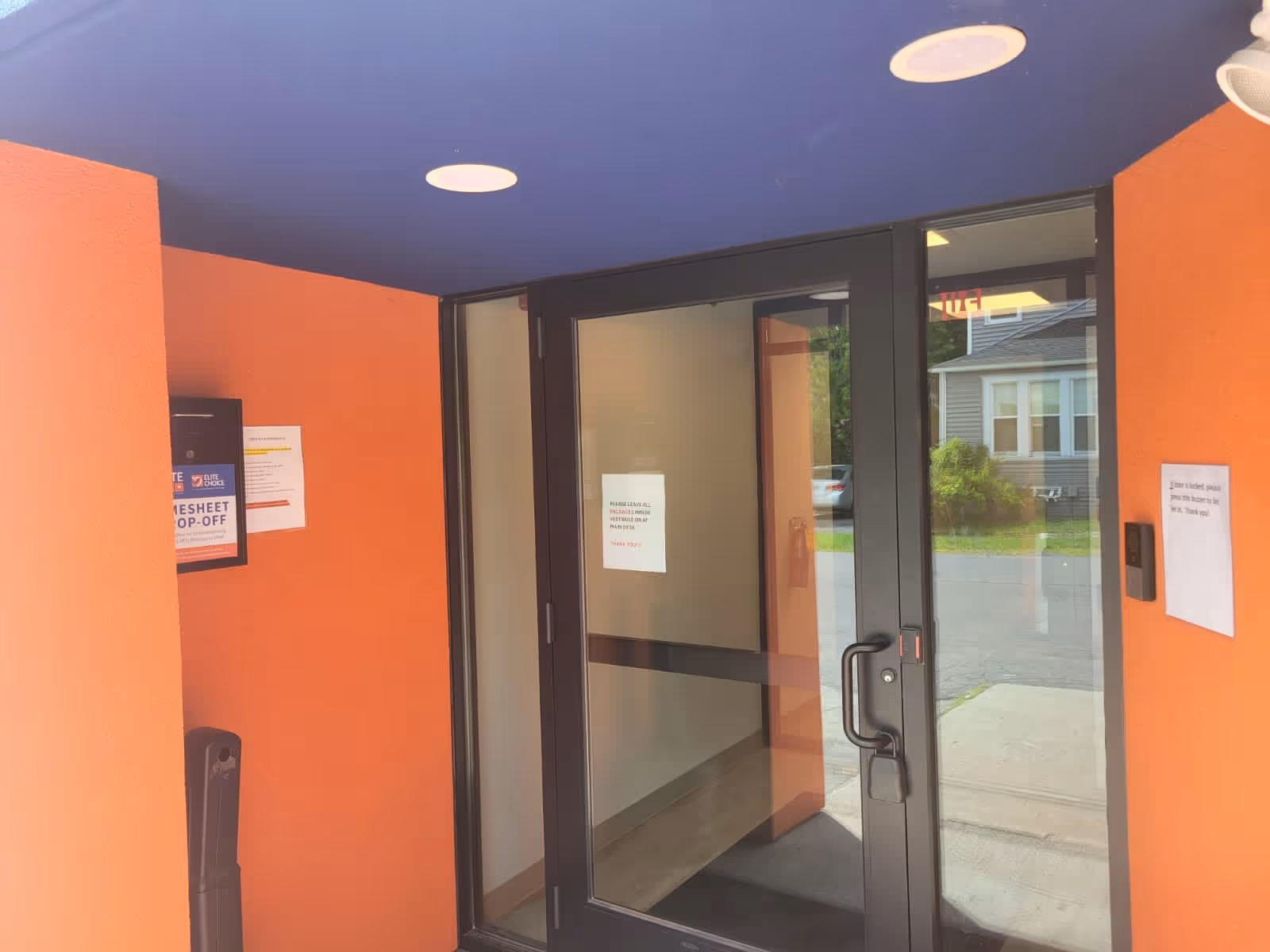 Orange-walled entryway with glass doors to the outside, purple ceiling, and round ceiling lights.
