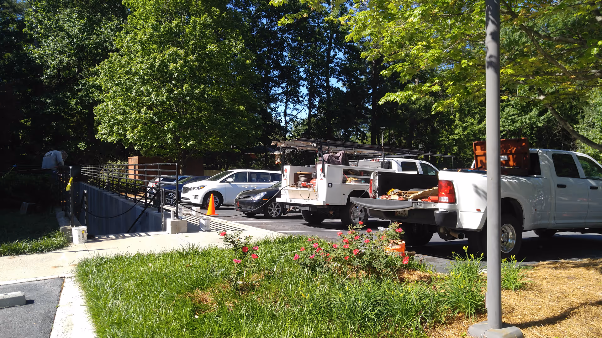 Exterior view of a senior home care facility with service trucks, ramp, and flower bed.