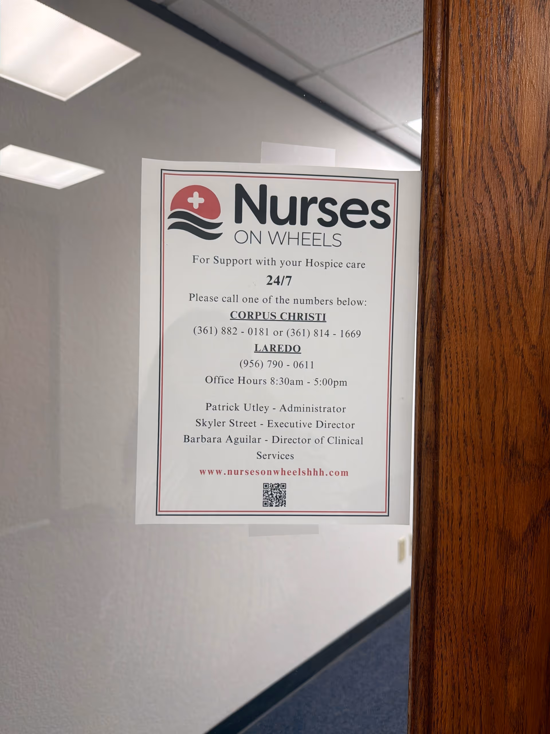 Poster for Nurses On Wheels posted on a hallway wall beside a wooden door.
