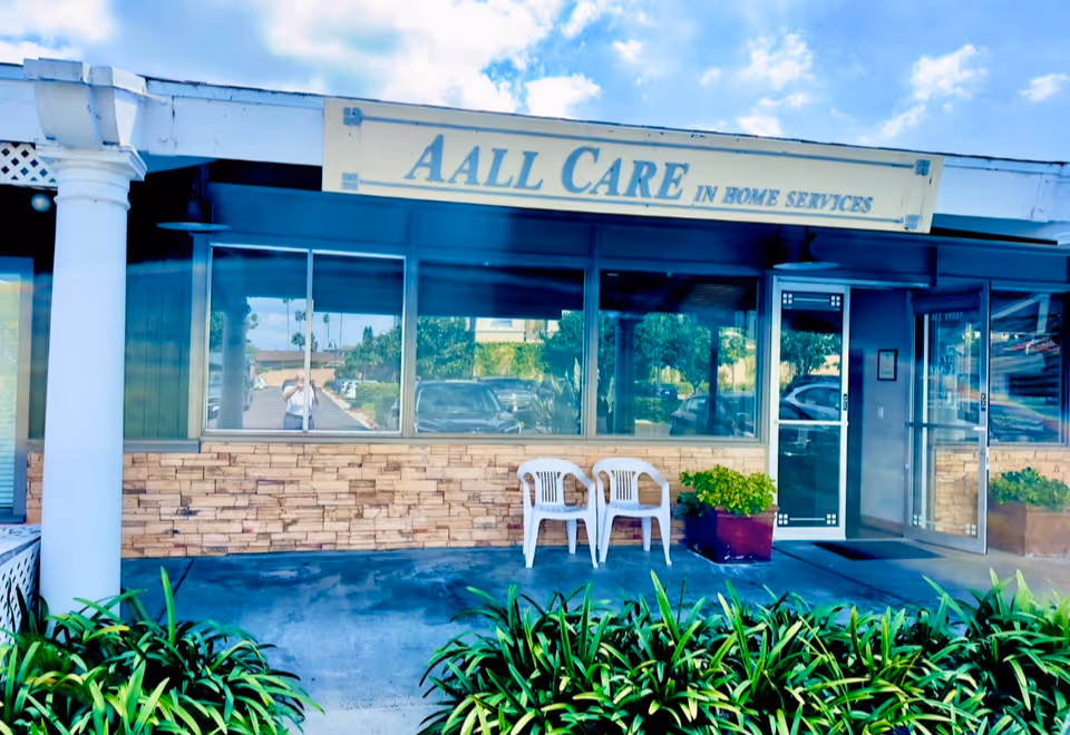Exterior of AALL Care In Home Services storefront with two white chairs outside.