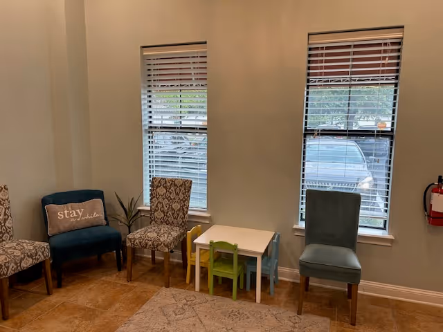 Small seating area in a senior living facility with chairs and a child-sized table.