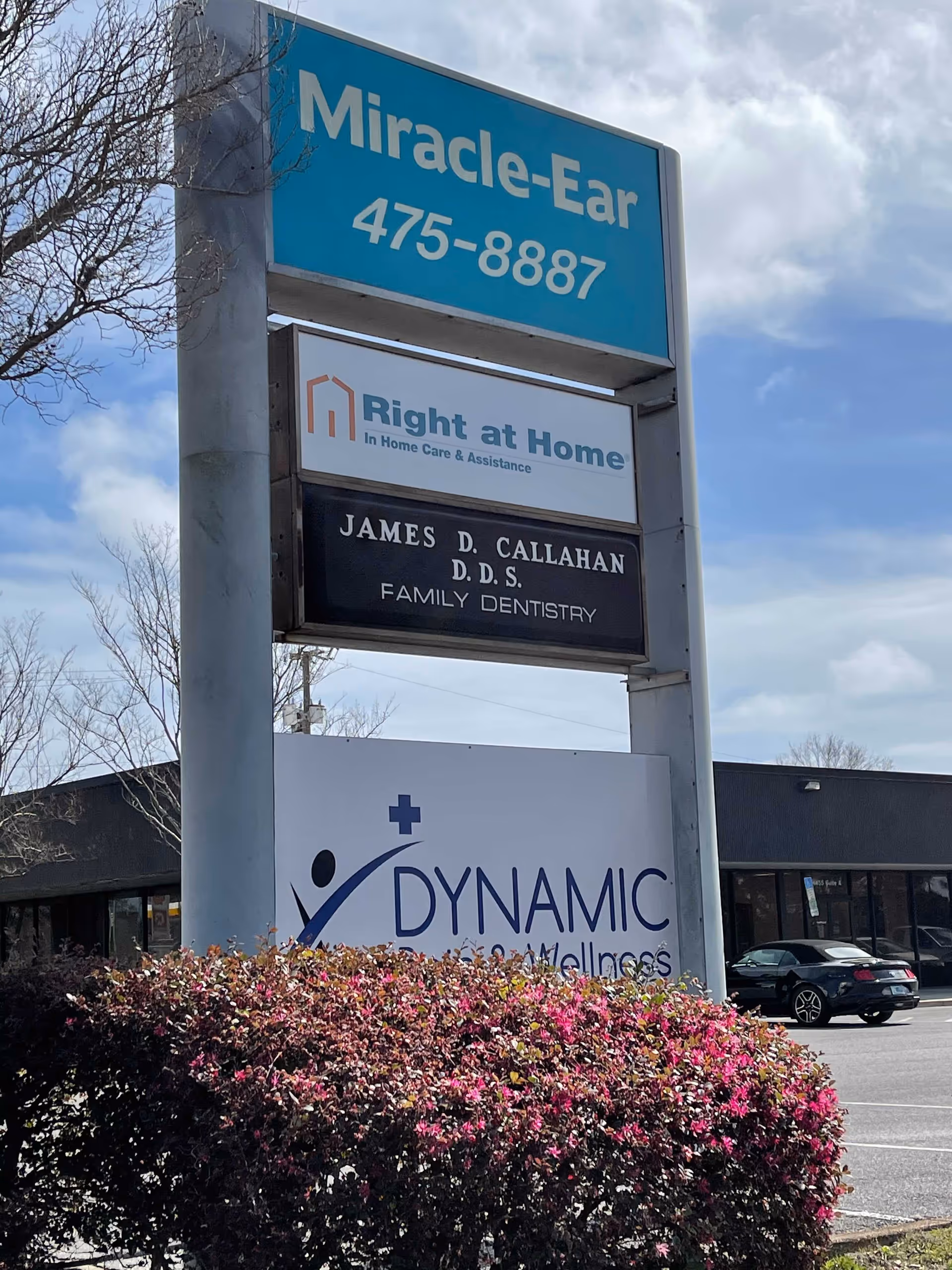 Tall outdoor sign for Right at Home in a parking lot with other businesses.
