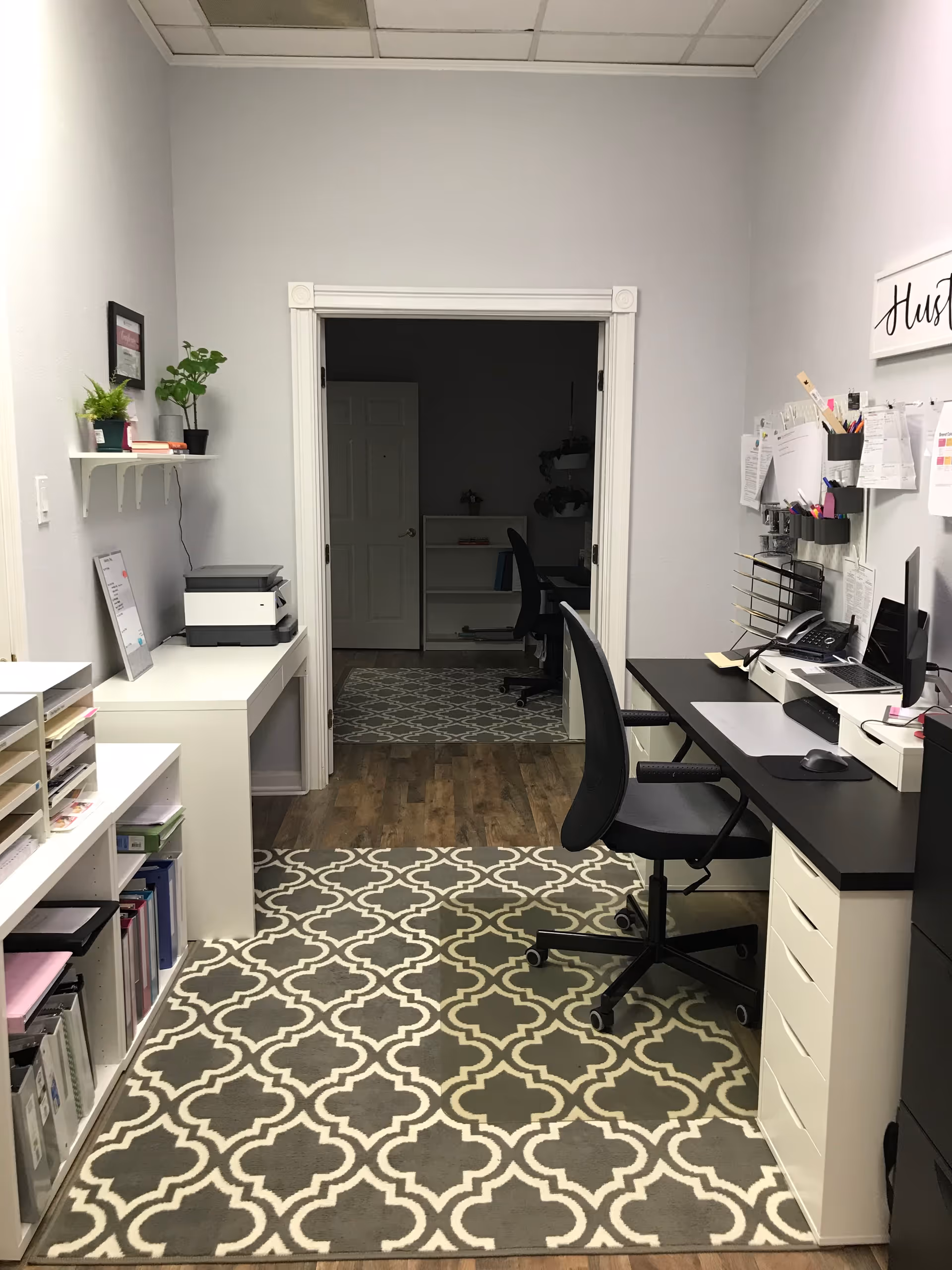 Office workspace with desks, chair, printer, shelves, and organized paperwork in a nursing office.