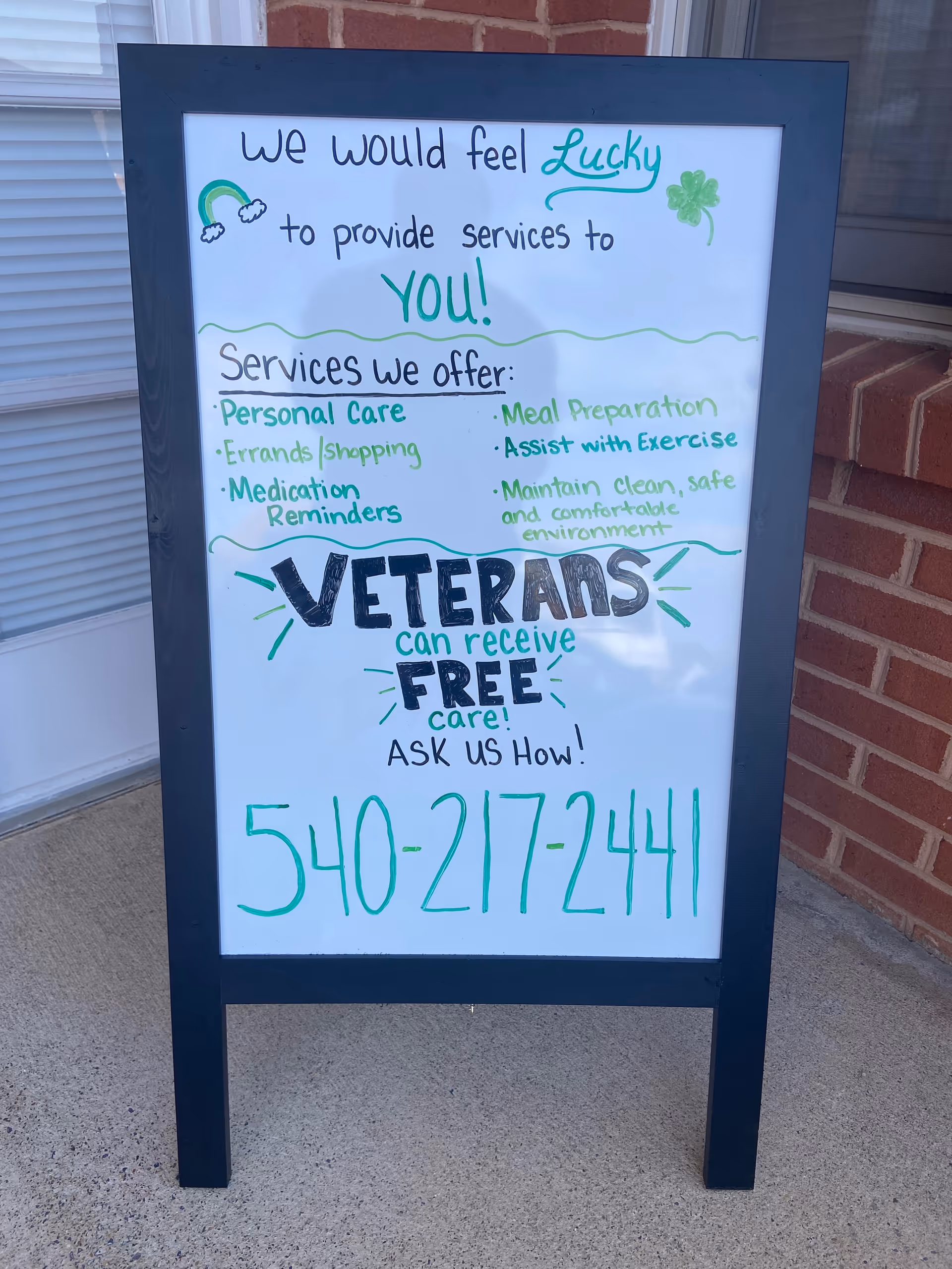 A sidewalk signboard outside a brick building advertising senior home care services