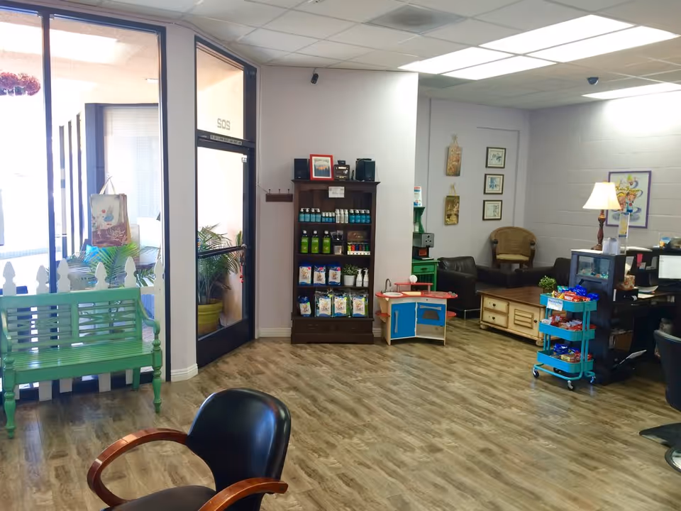 Lobby-style interior with seating, shelves, and a service cart in a senior living facility.