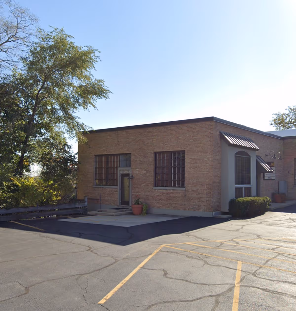 Exterior view of a brick senior living facility with a small entrance and parking.