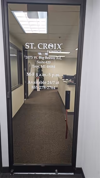 Glass door displays St. Croix Hospice signage and address; interior hallway visible beyond.