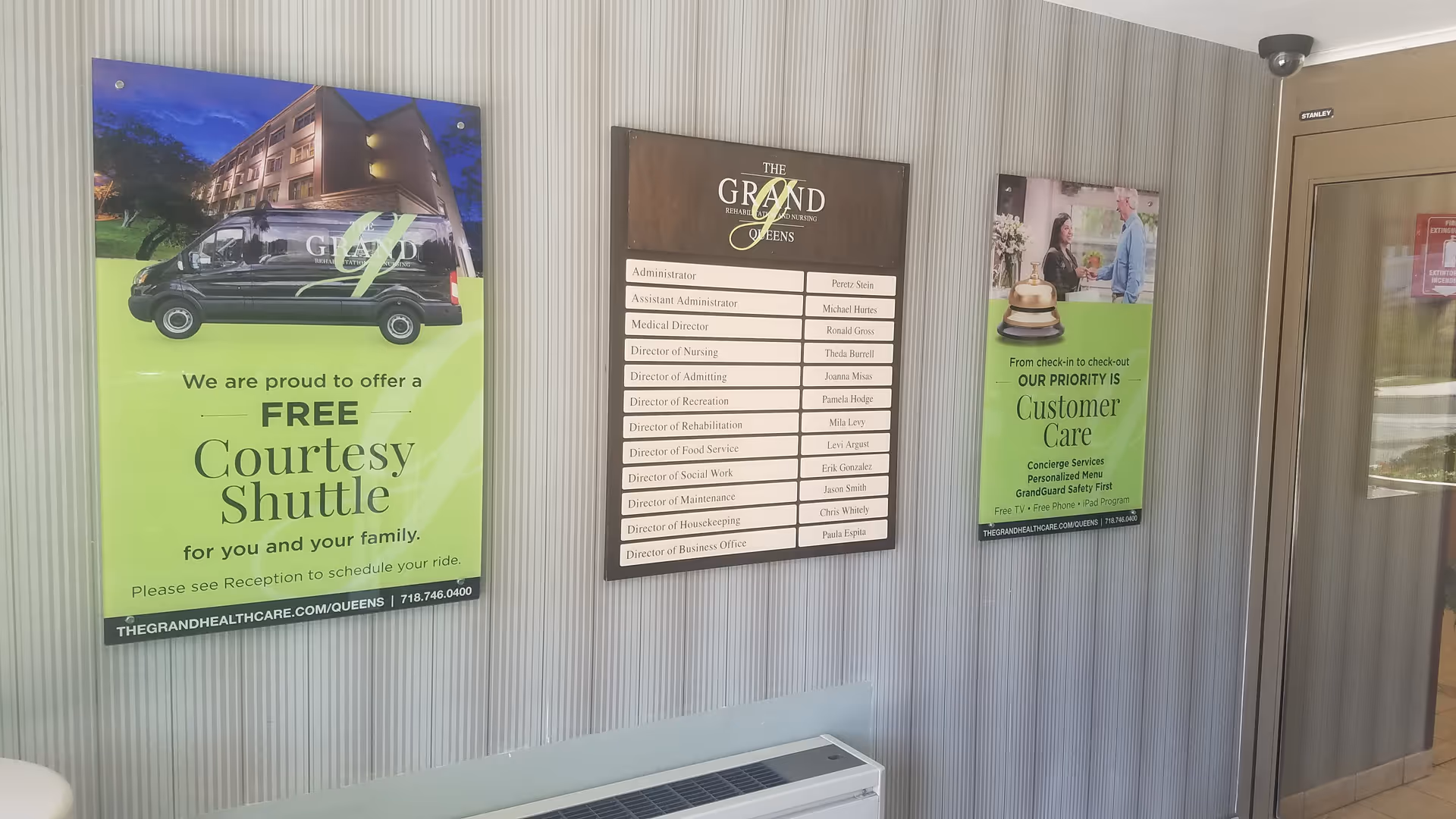 Interior wall with three signs, including a staff directory, in The Grand facility lobby.