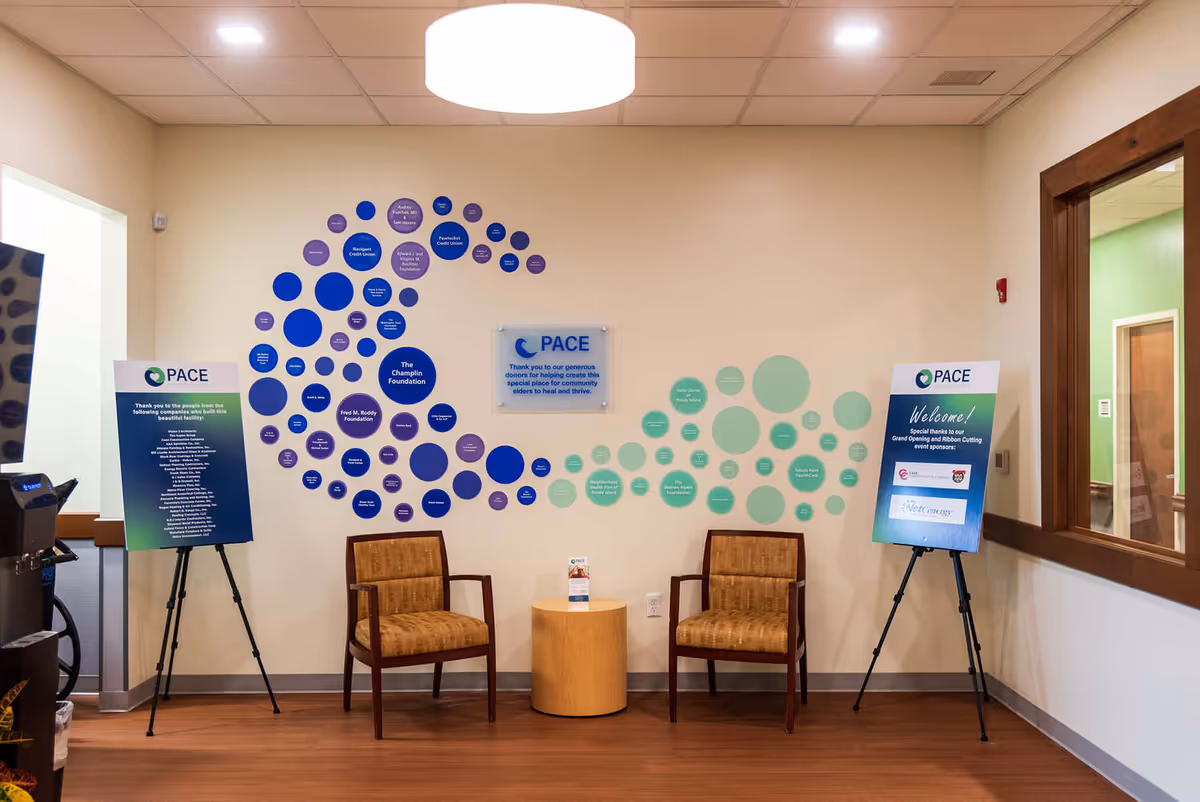 Waiting area with two chairs, round table, and wall of blue and teal circular wall art.