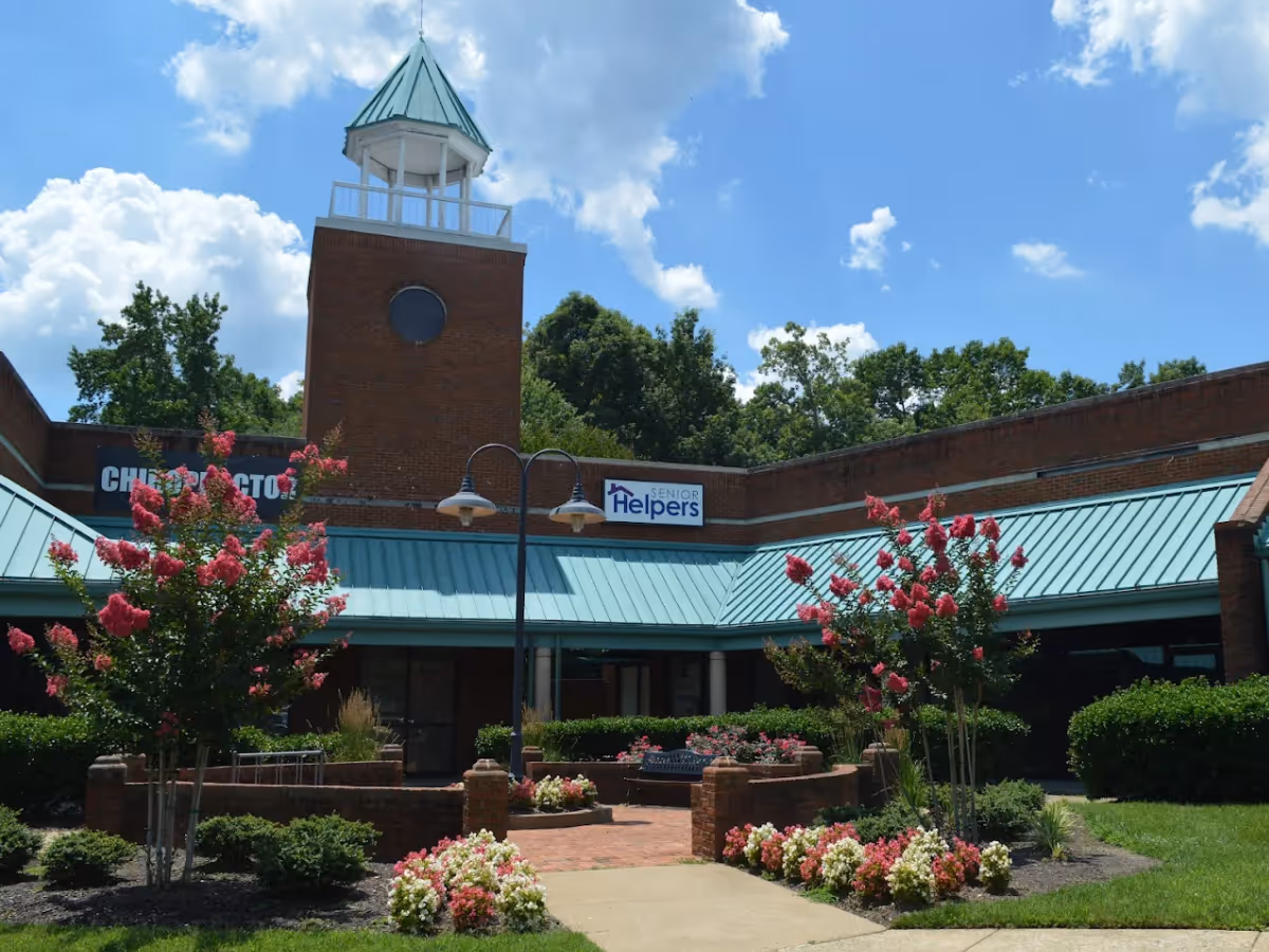 Exterior view of a Senior Helpers facility with brick walls, blue roof, and landscaped entrance.