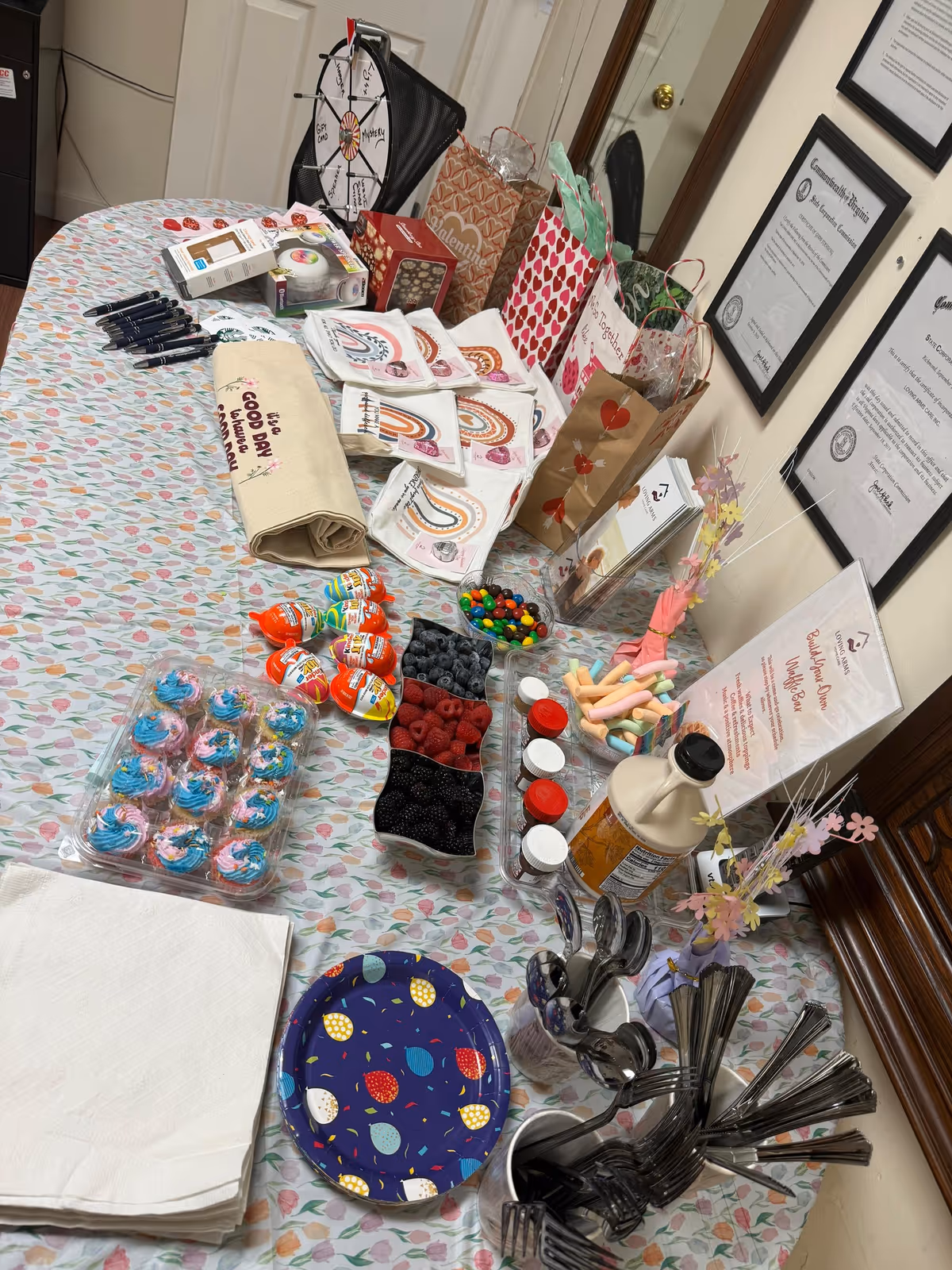 Interior table with cupcakes, snacks, gift bags, and party supplies for residents inside a care facility.