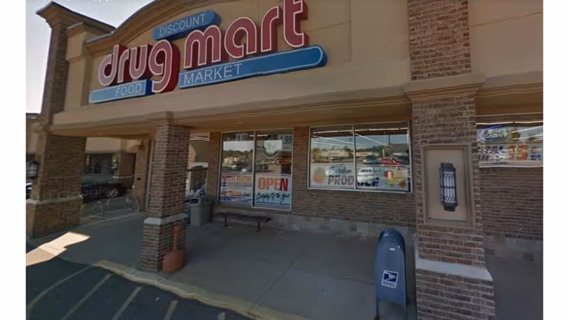 Exterior view of Discount Drug Mart storefront with brick columns and large sign.