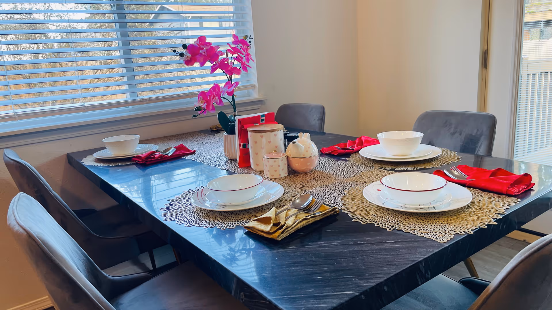 Bright dining room with a table set for meals and pink orchid centerpiece.