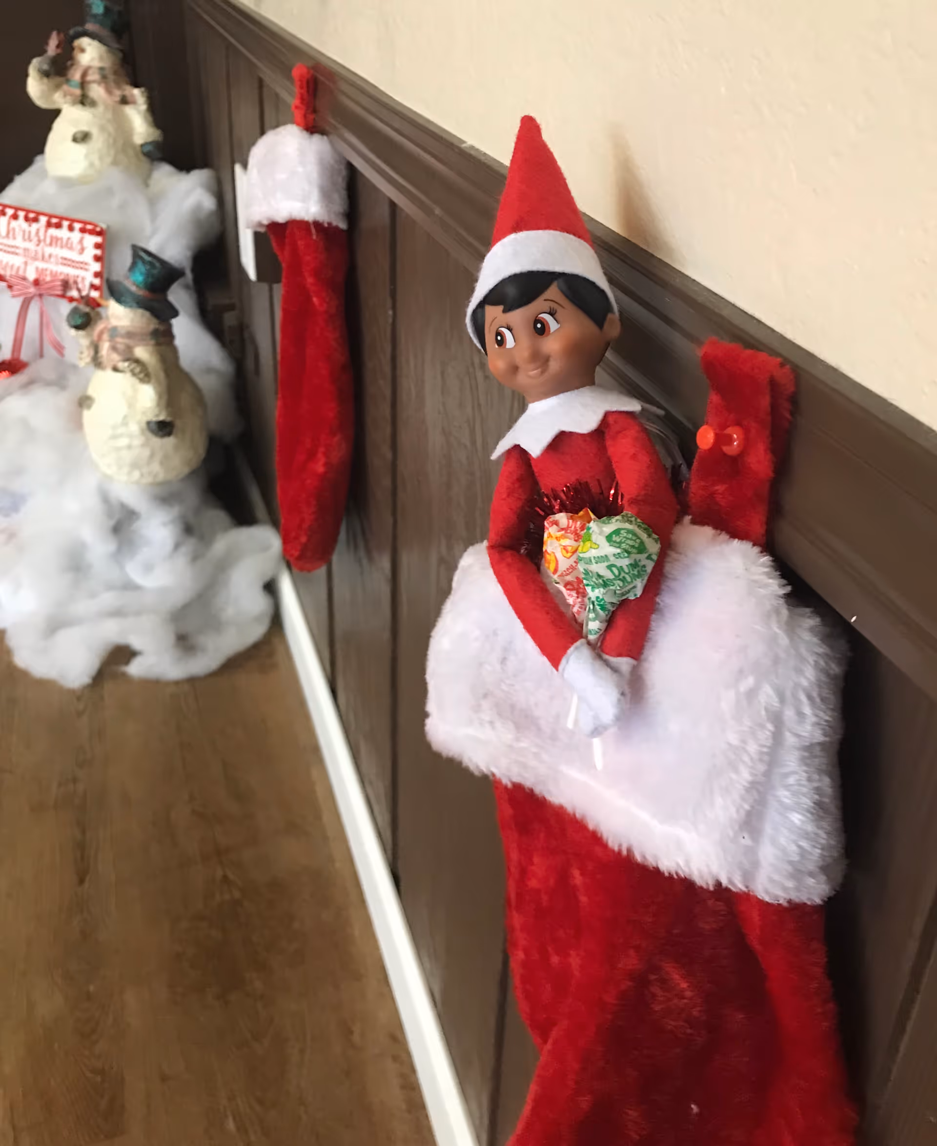 Indoor hallway decorated with a Christmas elf figure and red stockings.