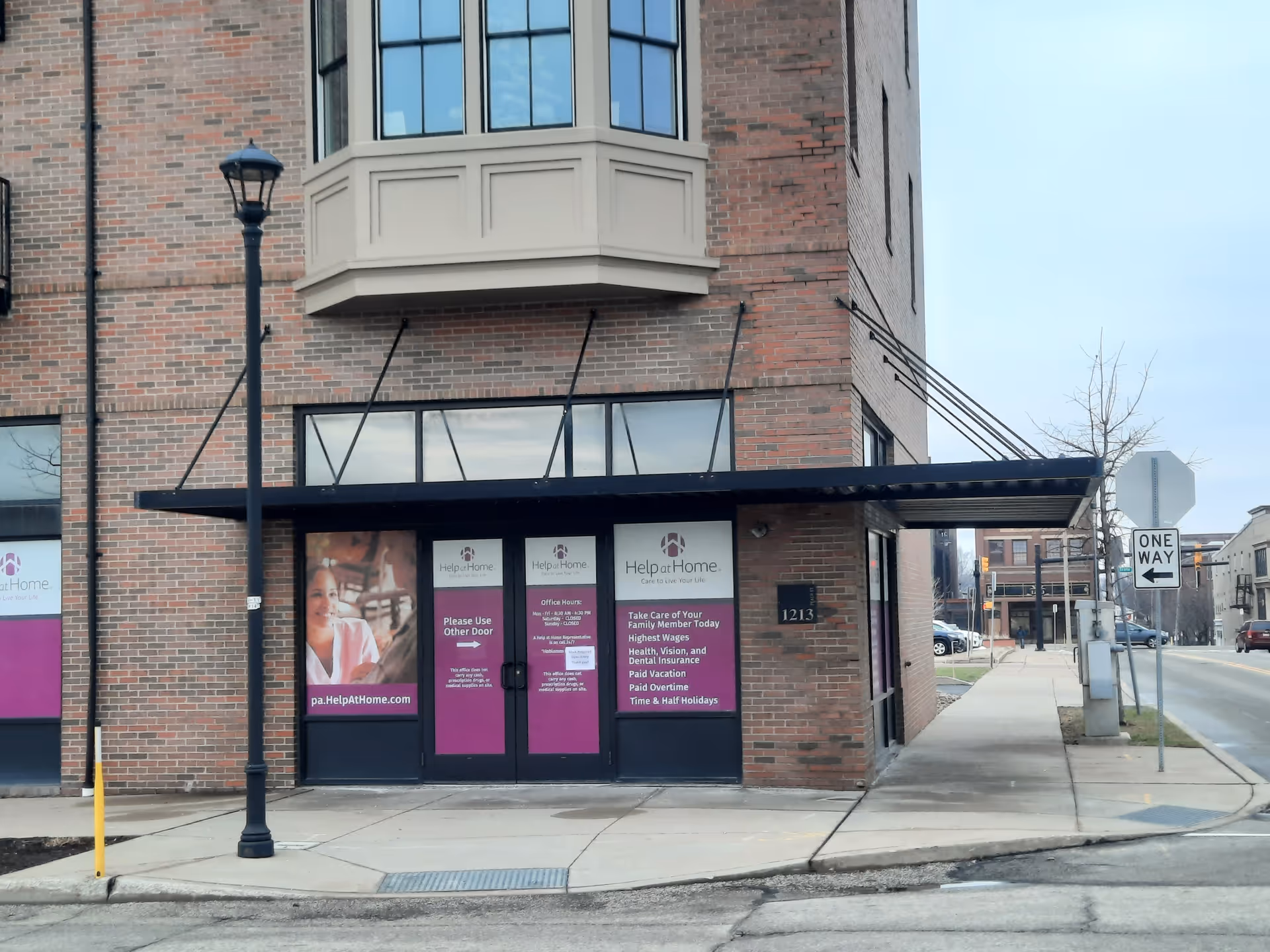 Brick building with glass doors under a canopy and Help at Home signage.