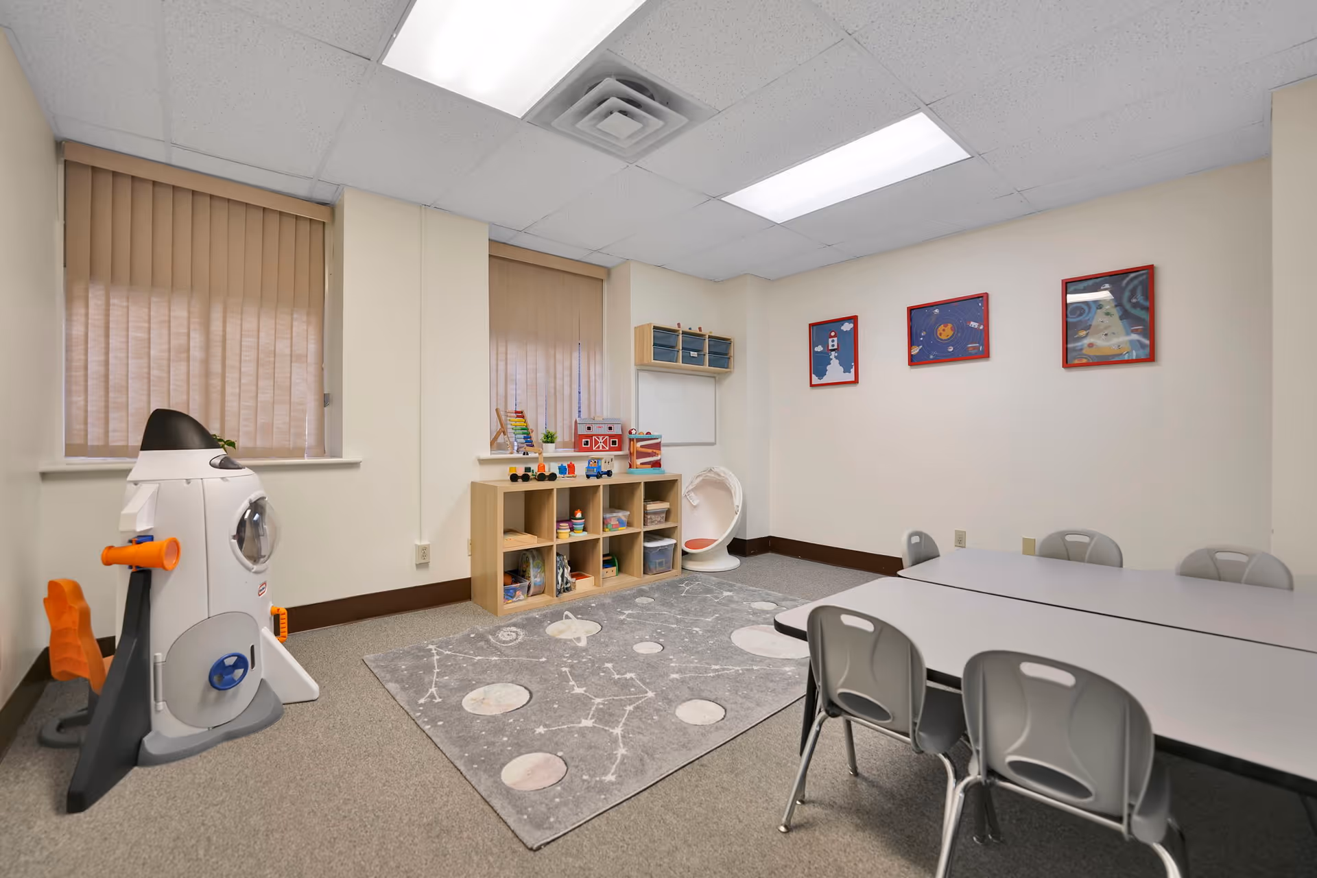 Activity room with toys, tables, and shelves in a senior living facility.