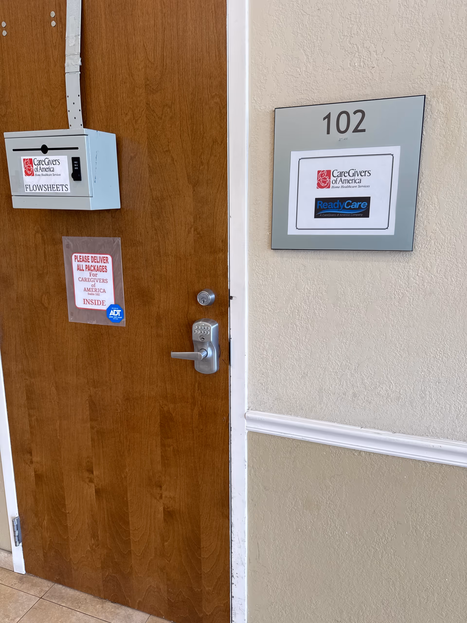 Interior hallway featuring a wood door marked 102 and CareGivers of America signage.