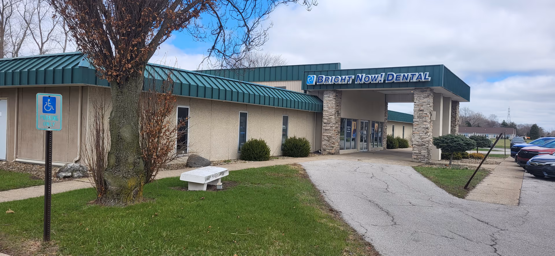 Exterior view of a single-story dental office with a wheelchair sign and parked cars.