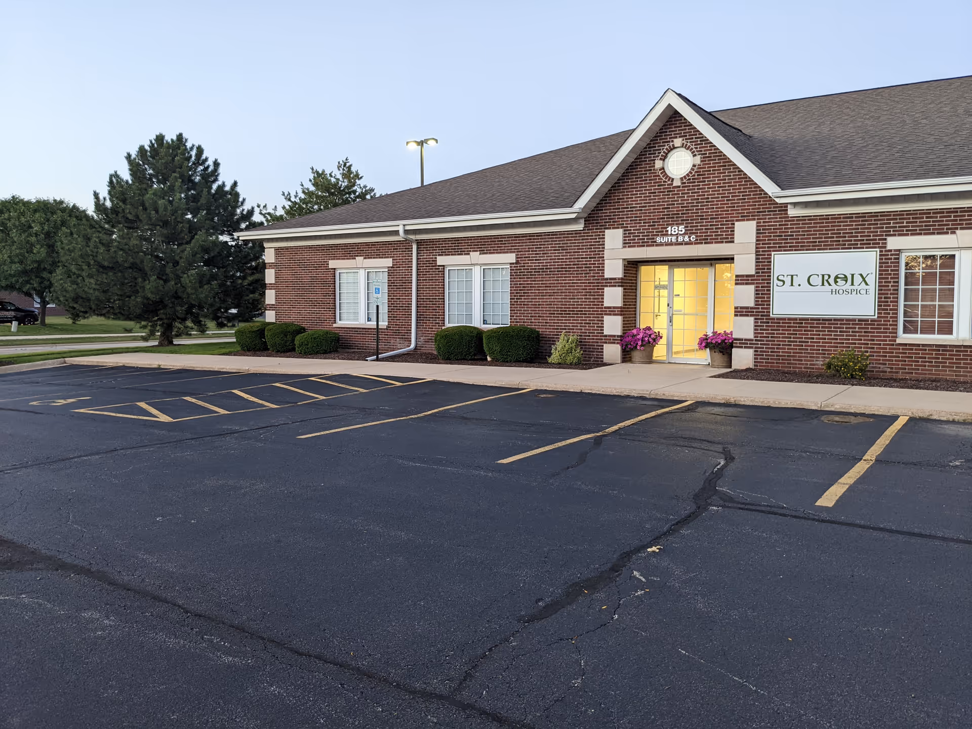 Brick facility with St. Croix Hospice sign and glass entrance, parking lot in foreground