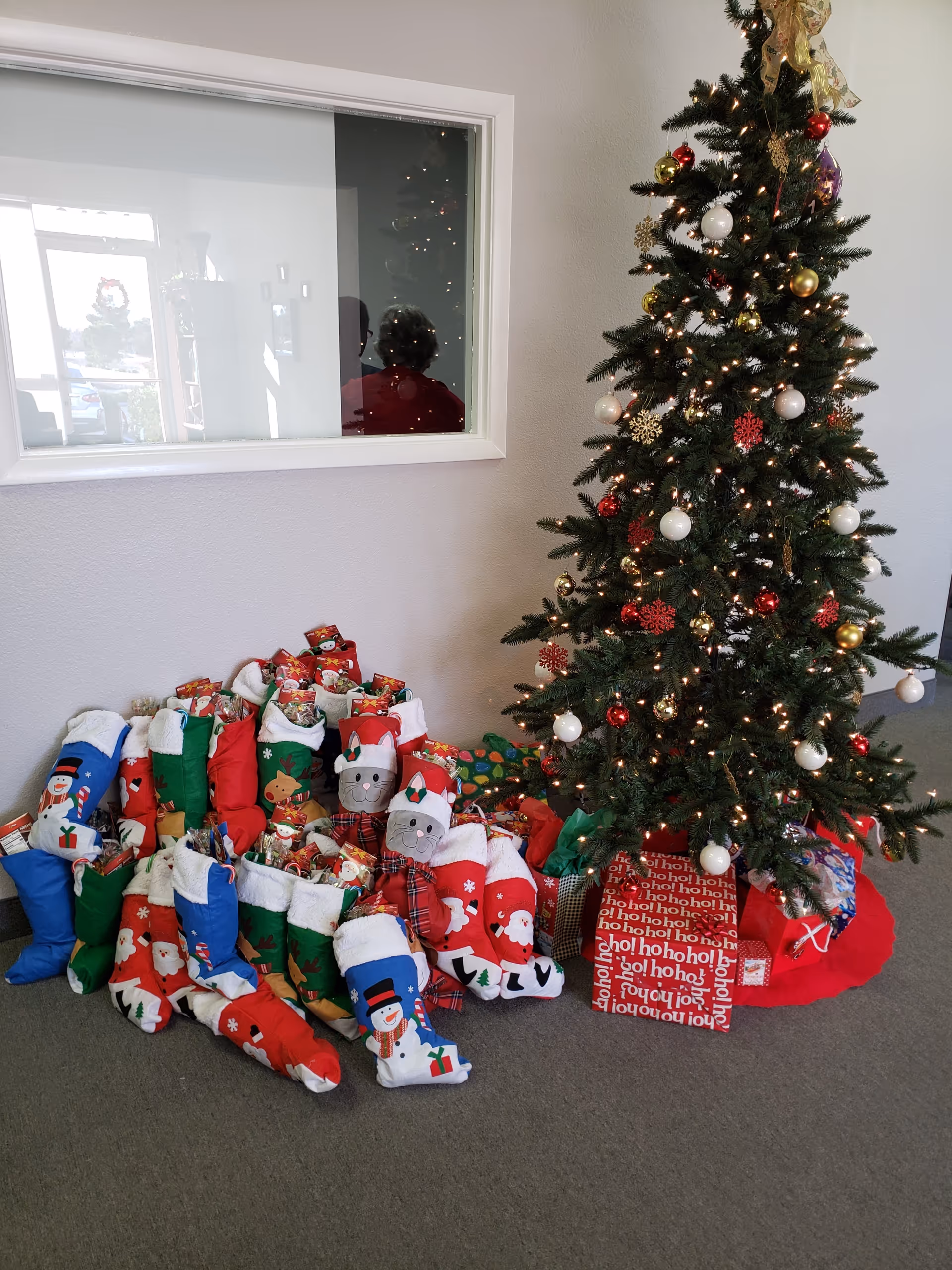 Indoor corner with a decorated Christmas tree, stockings, and wrapped gifts.