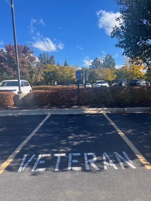 Outdoor parking lot with 'VETERAN' stencil on pavement and trees behind