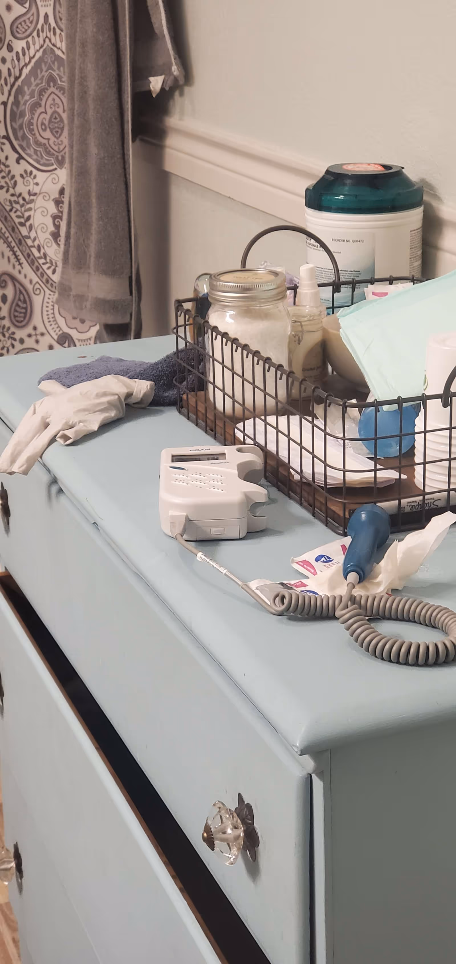 Medical supplies on a light blue cabinet with a wire basket and bottles