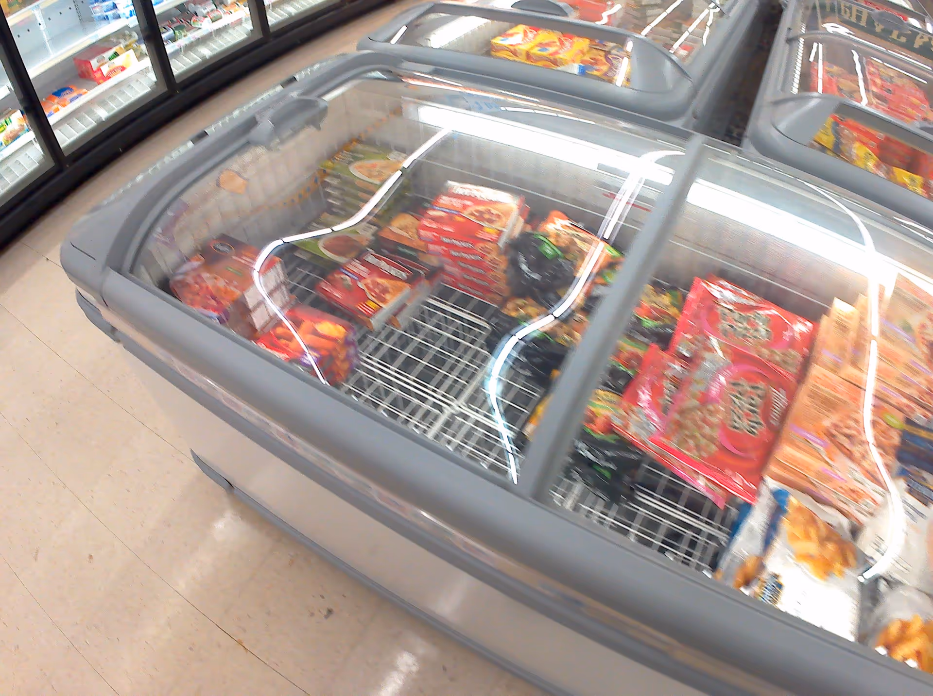 Overhead view of a grocery store freezer filled with frozen pizzas and snacks.