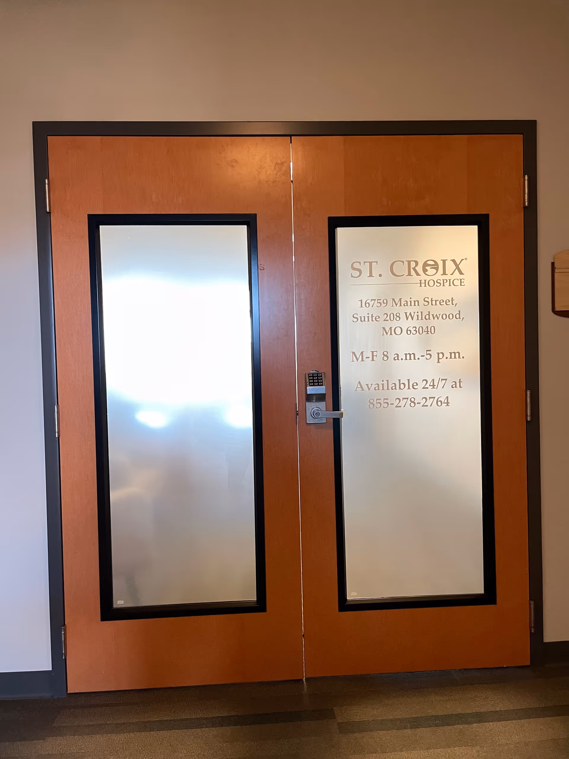 Double wooden doors with frosted glass panels and a St. Croix Hospice sign.