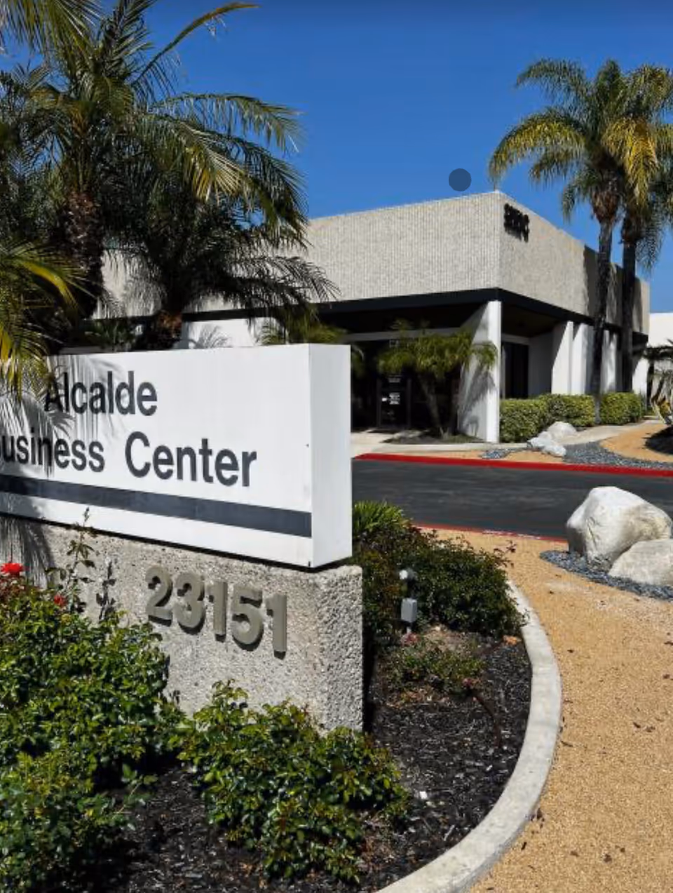 Exterior view of a modern building entrance with a landscaped front sign.