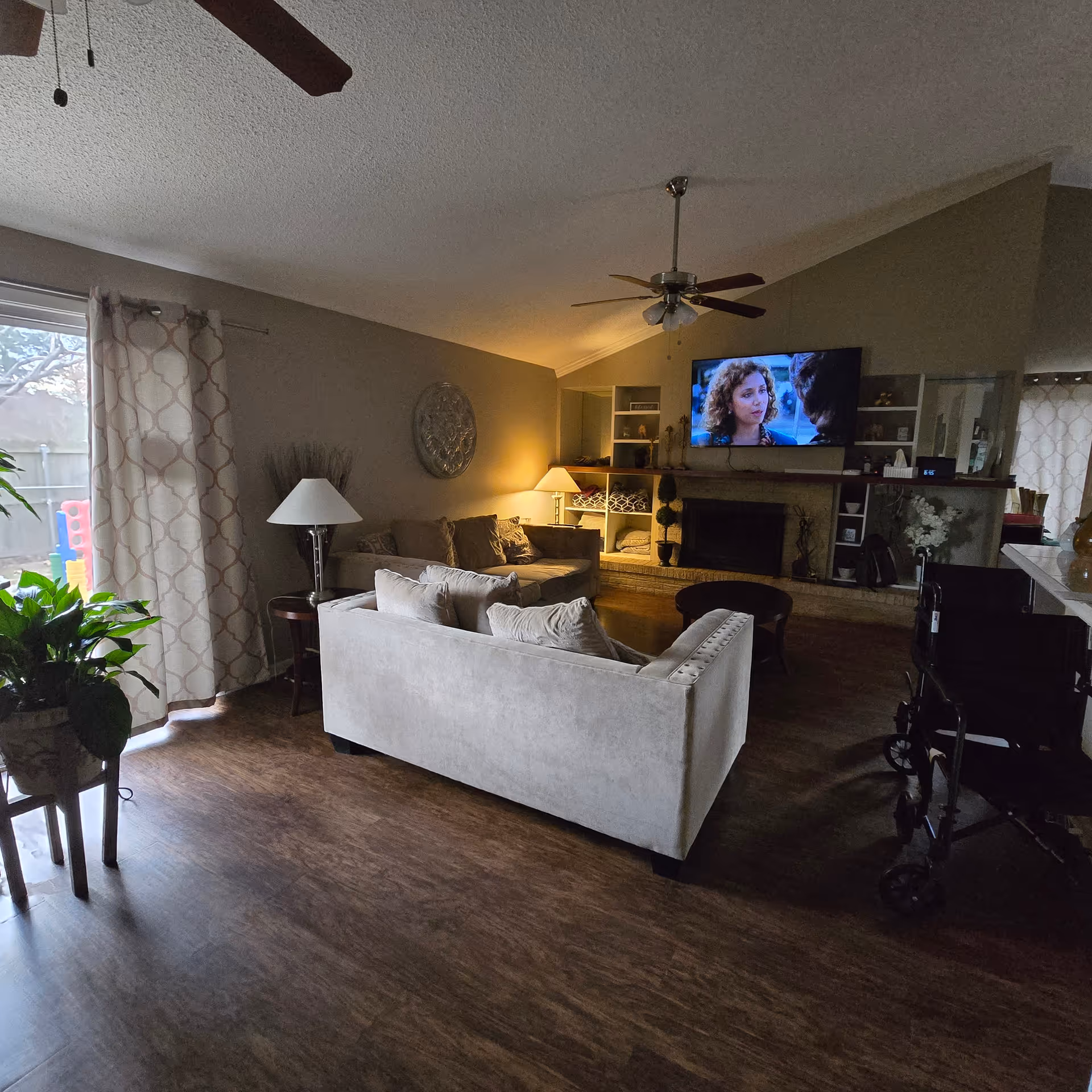Cozy living room with sofas, a TV, fireplace, shelves, and a walker nearby.