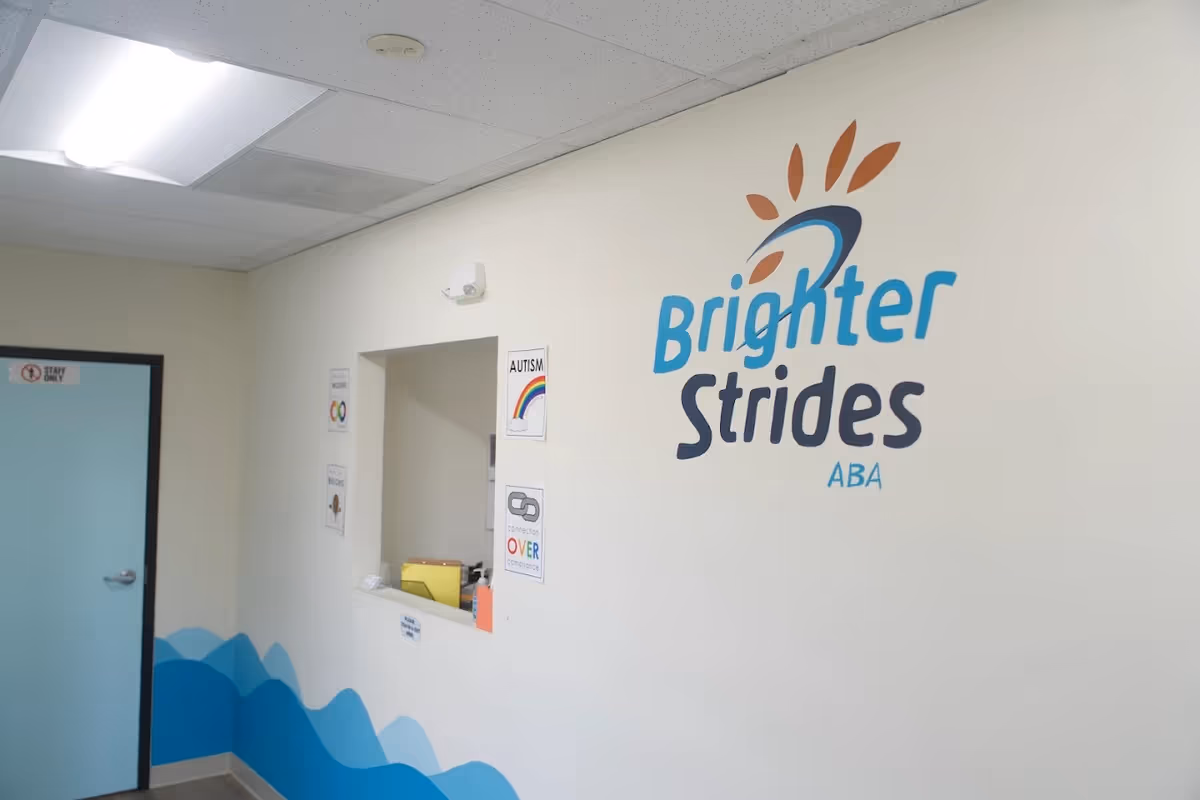 Interior hallway with Brighter Strides ABA logo, a reception window, and blue wave mural.