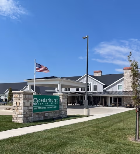 Exterior view of a senior living facility with Cedarhurst sign, flagpole, and entrance.