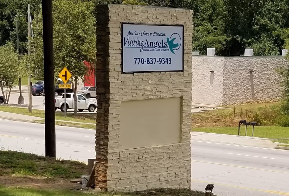 Stone sign for Visiting Angels Senior Home Care beside a roadside.