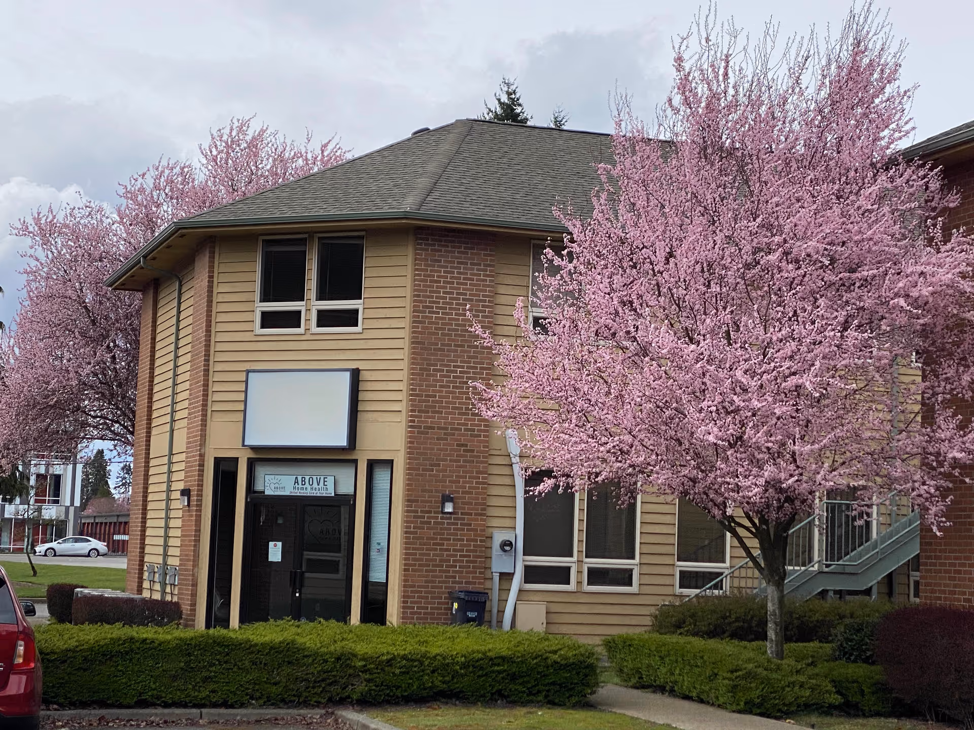 ABOVE Home Health entrance with pink flowering tree outside the building.