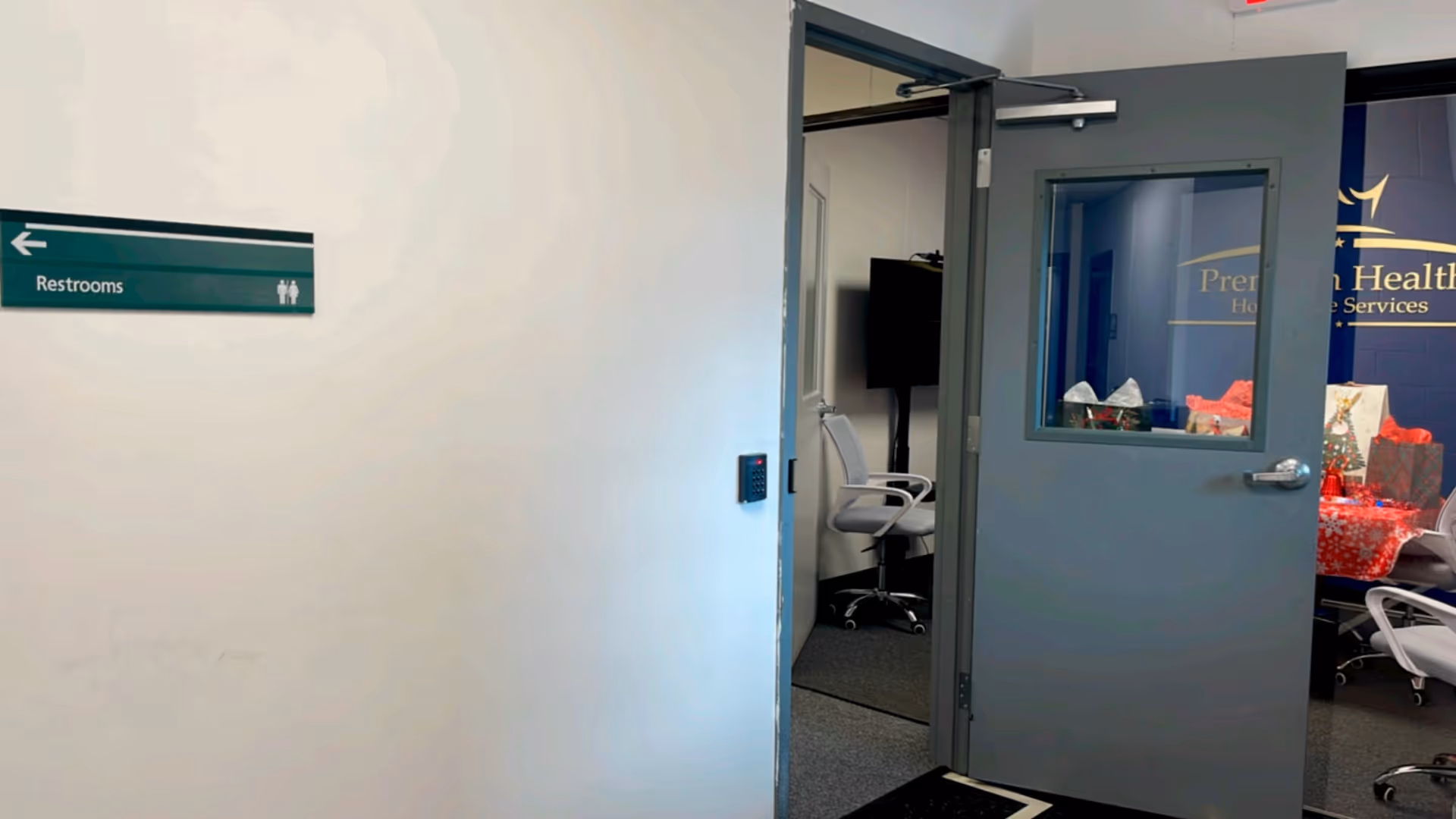 Open doorway leads to a small office/meeting room with chairs and a TV.