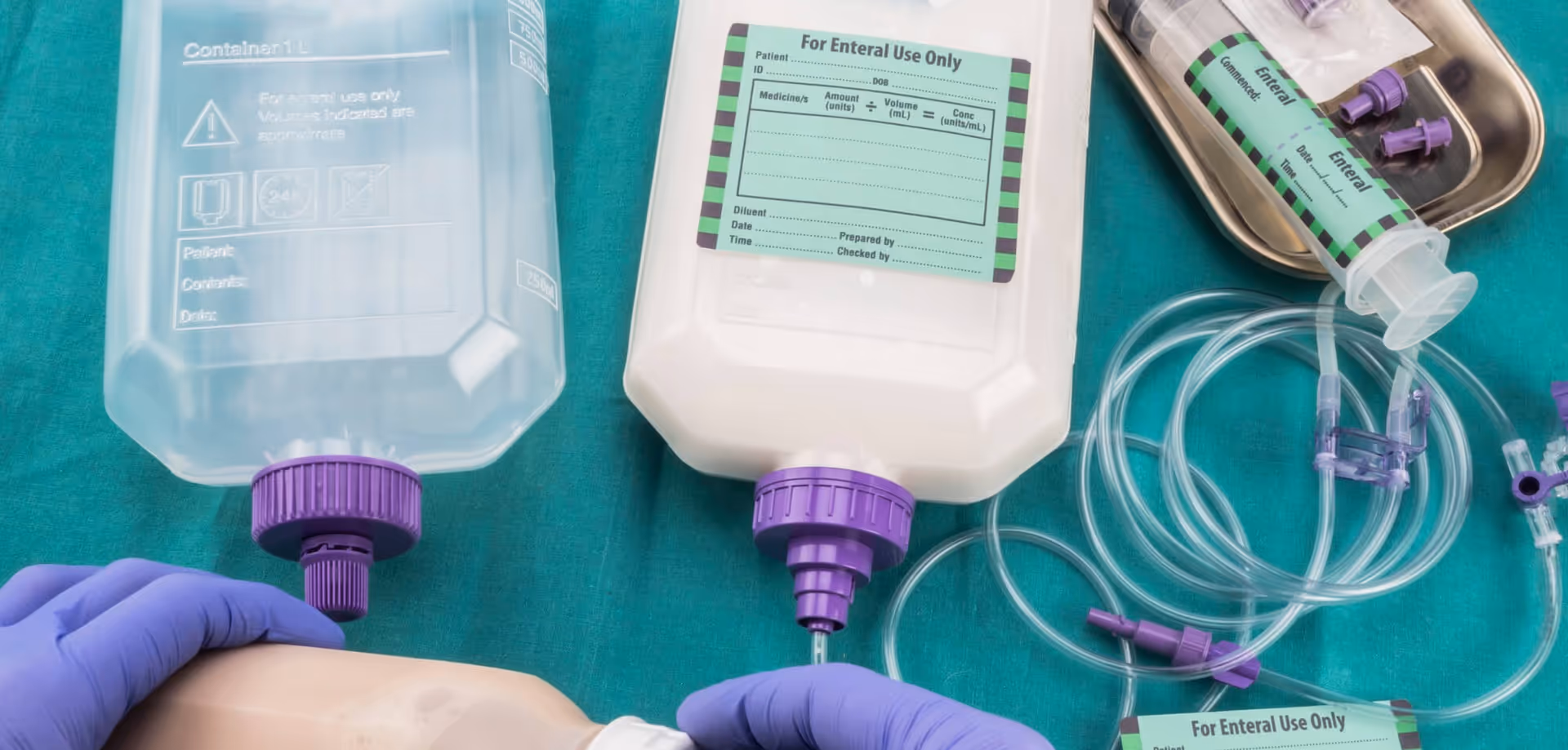 Close-up of IV bags, tubing, and gloved hands manipulating medical equipment.